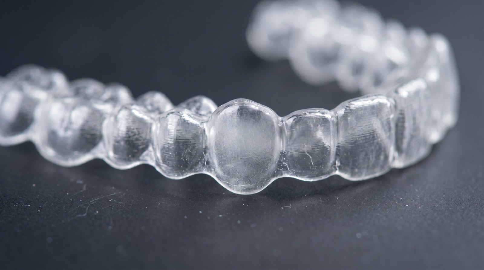 Direct-printed aligner showing a locally thicker pressure region against a thinner neighbouring wall